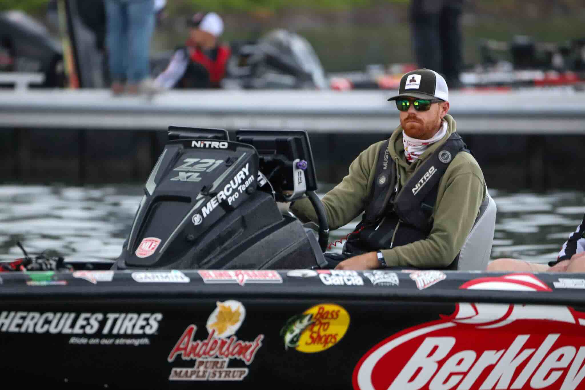 Josh Bertrand on a boat in a fishing competition with various sponsor logos on the boat.