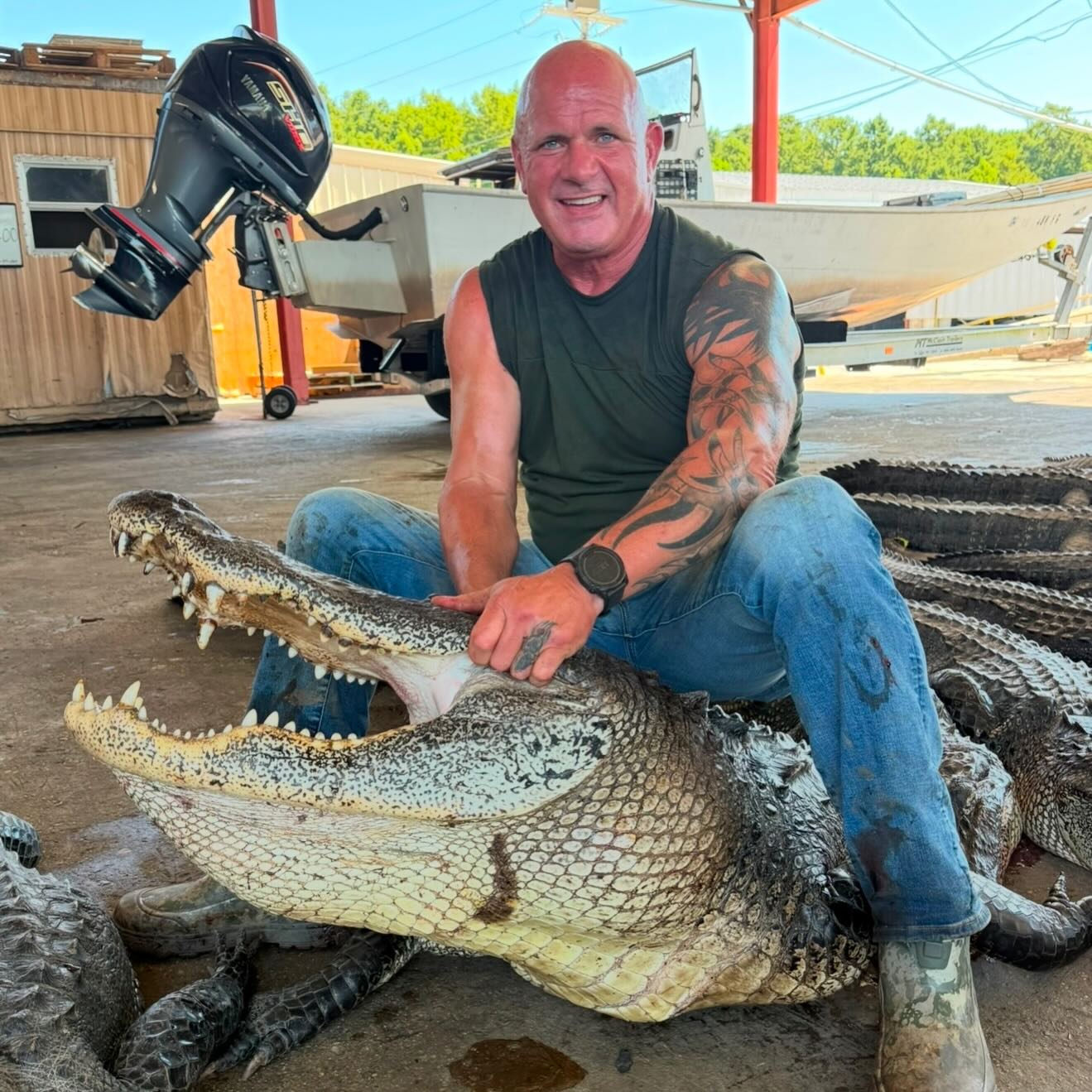 Ronnie Adams from swamp people sitting on a large alligator with a boat and equipment in the background