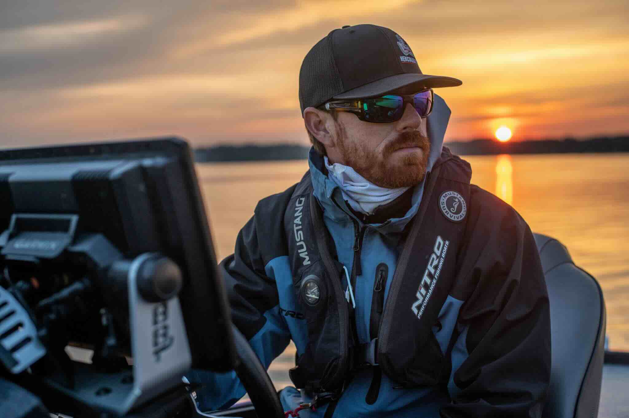 Josh Bertrand on a boat at sunset with fishing equipment