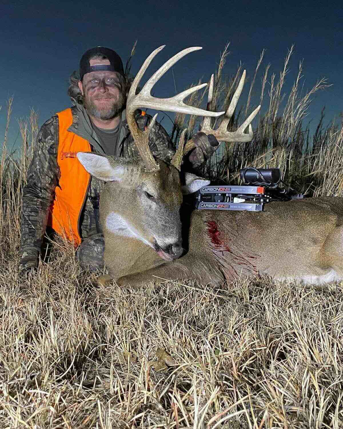 Matt Duff from Major League Bowhunter with a large deer in a field at night