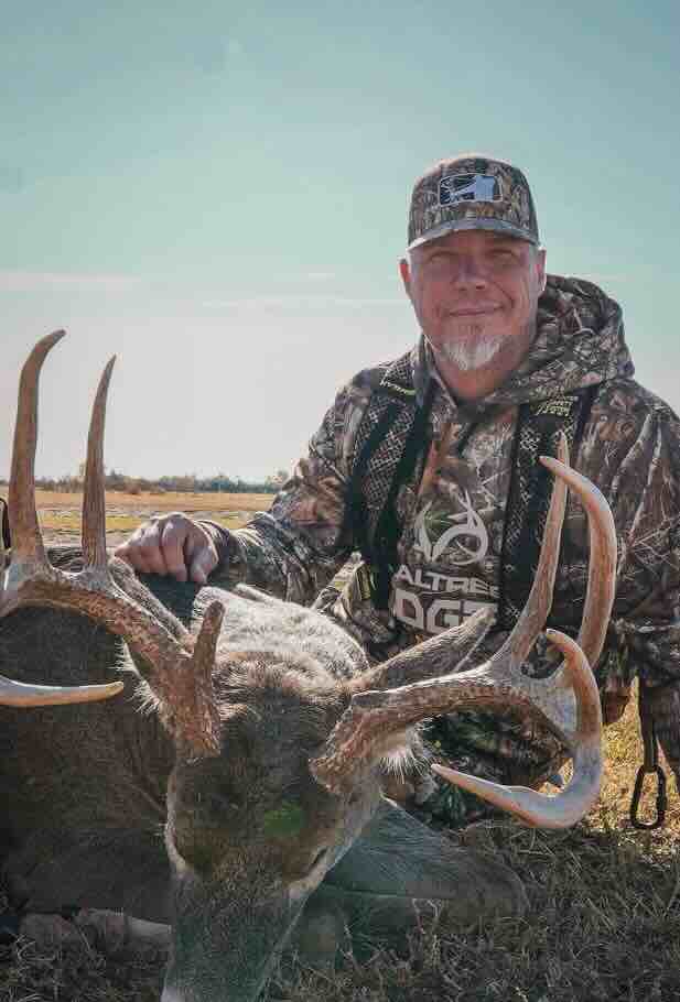 Chipper Jones posing with a large deer he has hunted, wearing camouflage clothing and a cap.